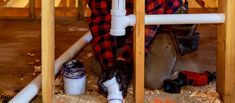 Plumber installing PVC pipes during new construction framing