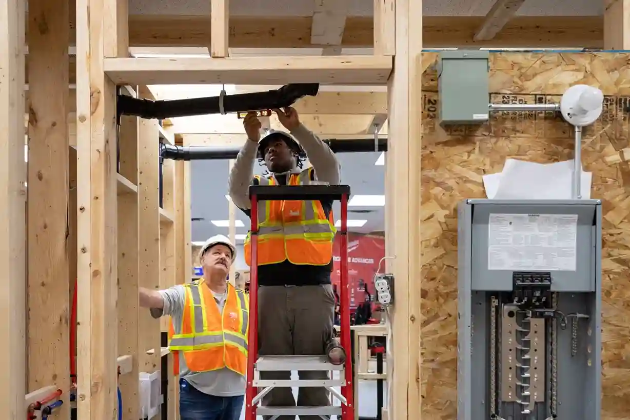 Construction workers installing plumbing and electrical systems inside building framing